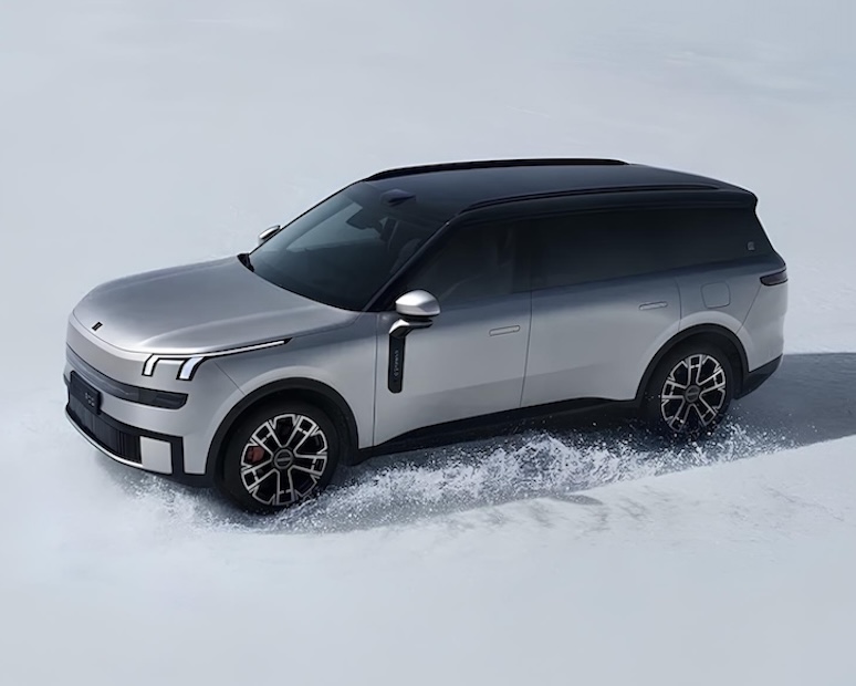 A silver Lynk & Co 900 SUV driving across a snowy surface, showcasing its sleek design and all-terrain capability.